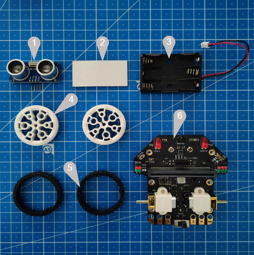 Imagen de conjunto de todas las piezas que formar el robot Maqueen numeradas del 1 al 6. Las piezas son: el sensor ultrasónico, material adhesivo de doble cara, el portapilas, las dos llantas, las dos bandas de rodadura y la placa.